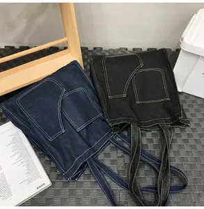 Detailed close-up of dark blue and black denim tote bags with dual front pockets and stitching