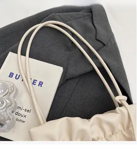 Close-up of cream white pleated bucket bag made of soft faux leather with slim handles