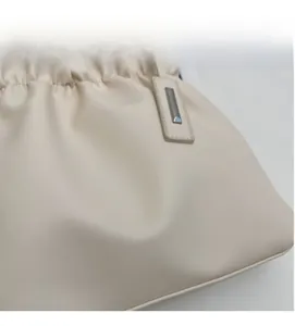 Detail of cream pleated leather bucket bag featuring silver logo and metal hardware
