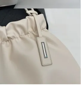 Close-up of cream pleated leather bucket bag with rectangular metal charm detail
