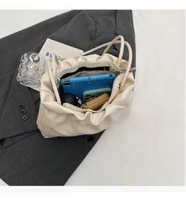 Interior view of off-white pleated cloud bag showing large capacity for tablet and phone