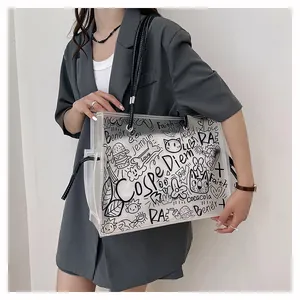Close-up of clear PVC tote bag with graffiti print and black straps on a fashion model