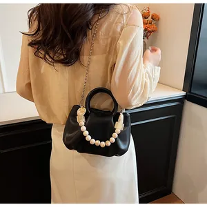 Detail of a black ruched dumpling bag featuring marble bead chain and metal shoulder strap