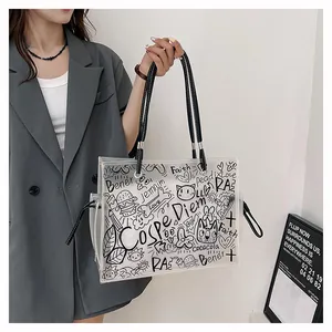 Detail of transparent PVC tote bag with black graffiti art and leather handles