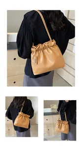 Close-up of a stylish camel pleated bucket bag with dual slim straps and metallic detail