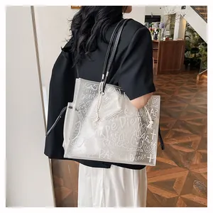 Macro detail of transparent PVC tote bag featuring white graffiti prints and black handles
