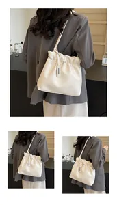 Detail of off-white pleated cloud bag with silver metal plate and thin crossbody strap