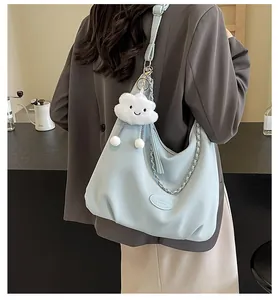 Detail of light blue hobo bag with lychee texture, silver chain and plush cloud charm