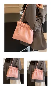 Detail of pink pleated crossbody bucket bag with silver pendant and smooth PU leather
