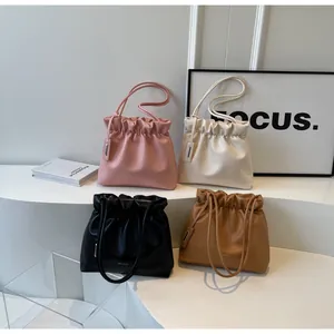 Detailed view of gathered pleat bucket bags in pink, beige, black, and caramel faux leather
