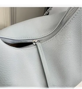 Detail view of silver metal zipper and blue pebbled leather texture on tote bag