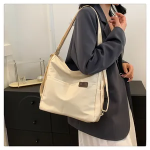 Detail der cremeweißen Nylon-Schultertasche mit Vordertasche und Logo-Aufnäher