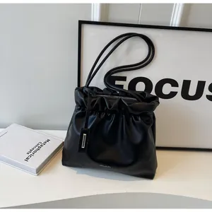 Detail view of black pleated dumpling bag with metal zipper and leather brand tag