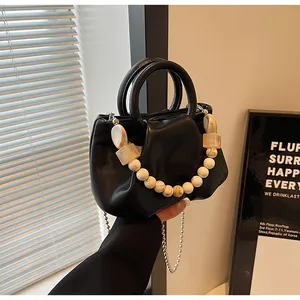 Detail of black pleated dumpling bag with ring handle and stylish beaded chain decoration