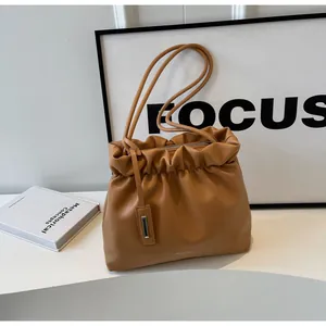 Detail of caramel pleated bucket bag in soft faux leather for casual daily commute