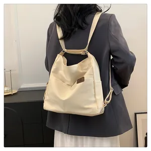 Detail des minimalistischen beigen Nylon-Rucksacks mit hochwertigem Logo-Patch aus Leder