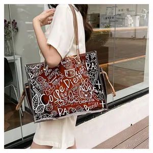 Detail of transparent PVC tote bag with brown leather handles and white graffiti patterns