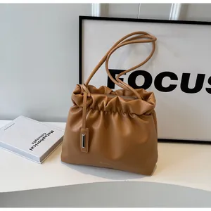 Detail of caramel pleated bucket bag featuring metallic zipper and thin shoulder straps