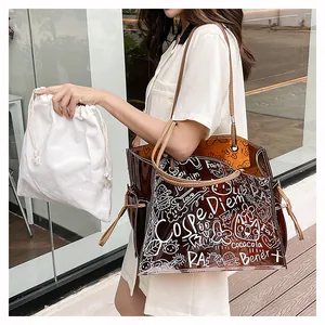 Detail of amber transparent PVC tote bag with white graffiti text and leather handles