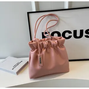 Detail of pink pleated bucket bag with dual handles and silver decorative pendant