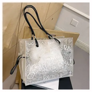 Detailed macro view of transparent PVC tote bag featuring white graffiti and black handles