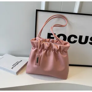 Close-up of pink pleated bucket bag featuring dual slim straps and silver zipper detail