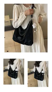 Detail of black large capacity hobo bag with metal chain and cute white cloud charm accessory