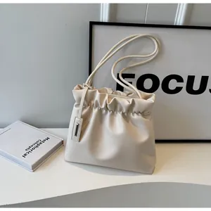 Close-up of cream pleated cloud bag with matte leather texture and silver metal charm