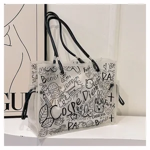 Detail of transparent jelly tote bag with black graffiti prints and faux leather straps
