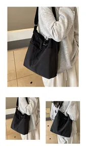 Detail der schwarzen Kordelzug-Tragetasche aus Nylon mit Seitentasche und schlichtem Design