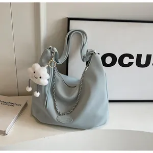 Detail of light blue tote bag with litchi grain texture, silver chain, and cloud charm