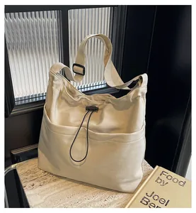 Detail of cream drawstring bucket bag showing front pockets and adjustable strap