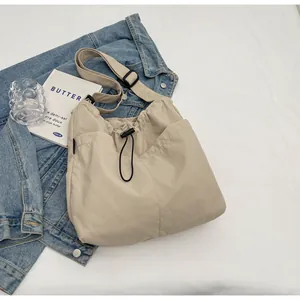 Detailansicht der beigen Nylon-Umhängetasche mit Kordelzug und schwarzem verstellbarem Gurt
