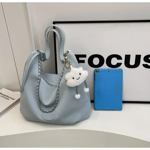 Detail of light blue lychee leather hobo bag with silver chain and plush cloud pendant