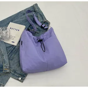 Detail der lila Nylon-Umhängetasche mit Kordelzugtasche und verstellbarem Riemen