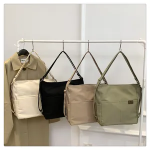 Detail von vier vielseitigen Canvas-Schultertaschen in Weiß, Schwarz, Beige und Grün