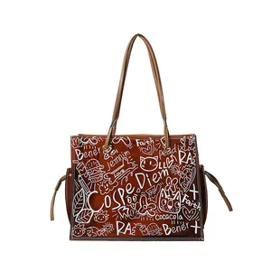 Large brown leather tote bag with white graffiti patterns and two shoulder straps