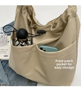 Close-up of front pockets on beige bucket bag showing convenient storage for phone and umbrella