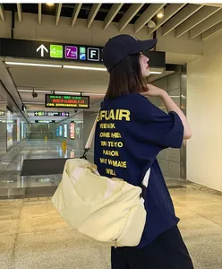 Amplia bolsa de deporte crema con compartimento para zapatos en una estación de metro