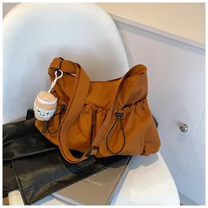Detailed view of caramel drawstring bucket bag with plush coffee cup charm on chair