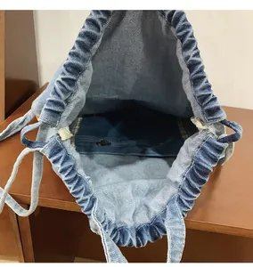Vue de dessus du sac à dos en denim avec cordon, doublure intérieure et poche zippée
