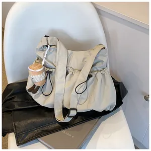 Detail of beige drawstring bucket bag with plush coffee cup charm on a white chair