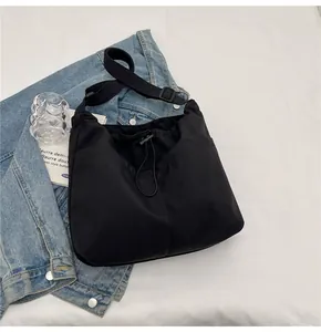Flat lay of black drawstring nylon bucket bag with adjustable strap and casual props
