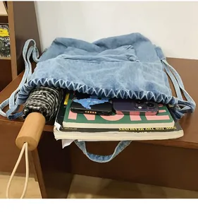Détail du sac à dos en jean bleu clair avec cordon de serrage montrant le tissu et l'espace