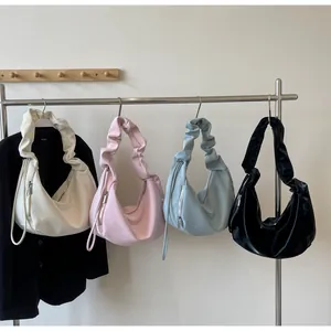 Detailed row of pleated soft leather underarm bags in cream, pink, blue, and black