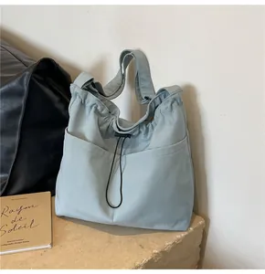 Macro shot of light blue drawstring bucket bag with dual front pockets on stone base