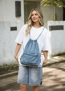 Détail du sac à dos en jean bleu avec cordon de serrage et poche extérieure zippée