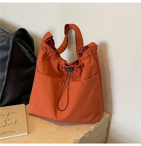 Detail view of brick red drawstring bucket bag showing canvas texture and front pocket