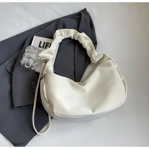 Detail view of cream hobo bag with pleated handle and metallic side zipper decoration