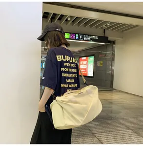 Foto callejera de bolsa de viaje de nailon beige con correa al hombro y logotipo